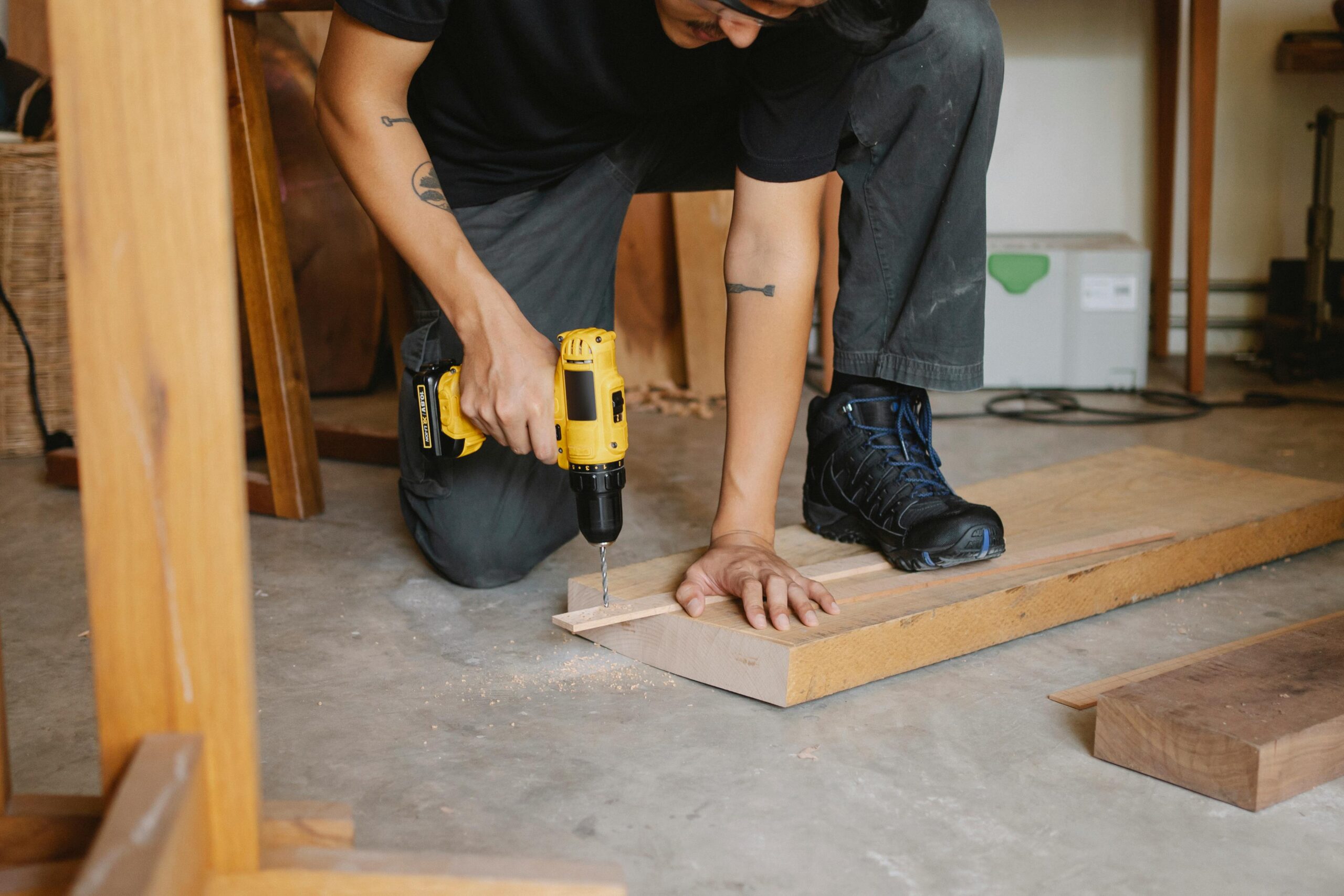 Services A focused craftsman using a drill to work on a wooden project in a workshop setting.