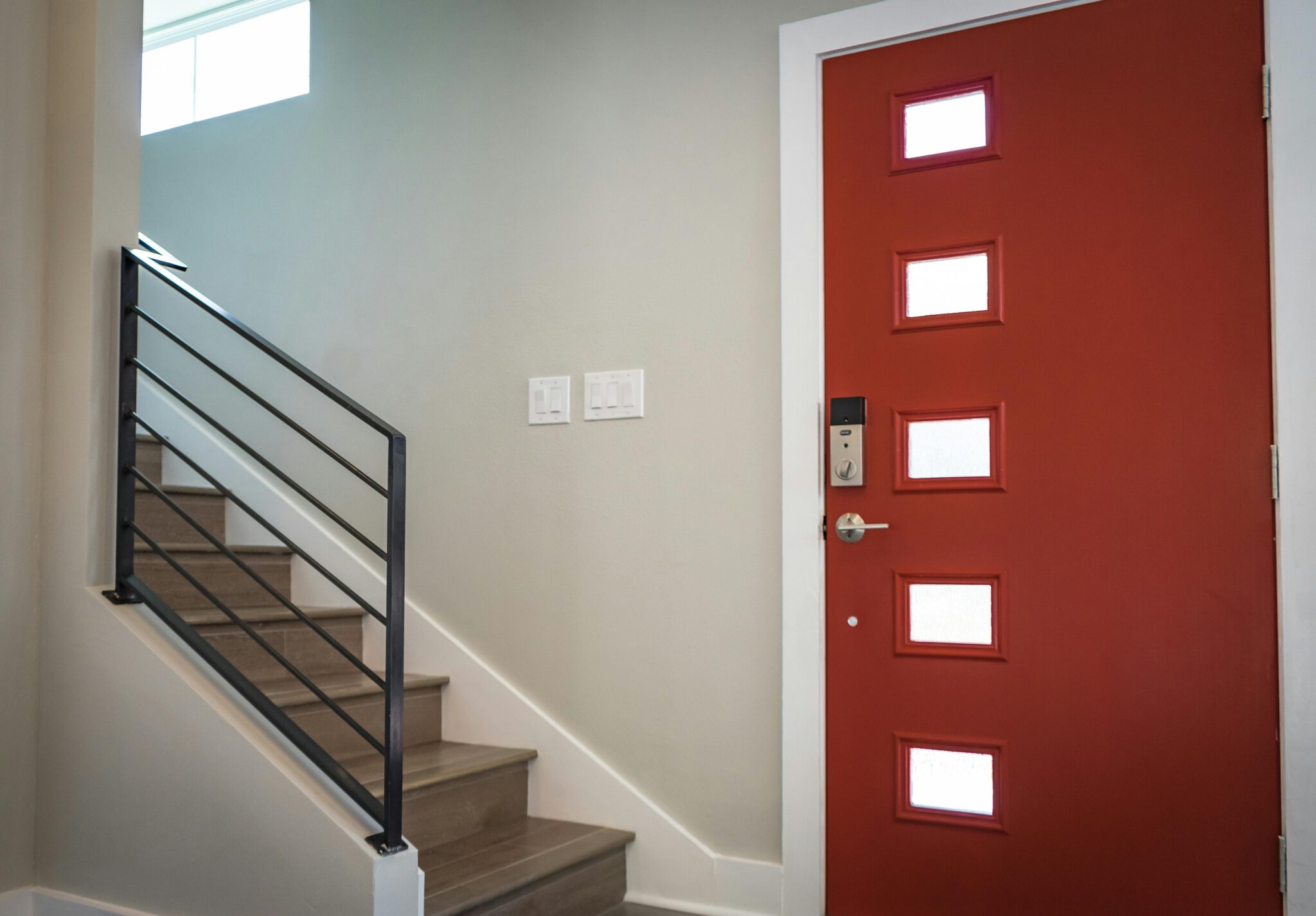 Services Contemporary interior with a vibrant red entrance door and stairs, showcasing minimalist design.